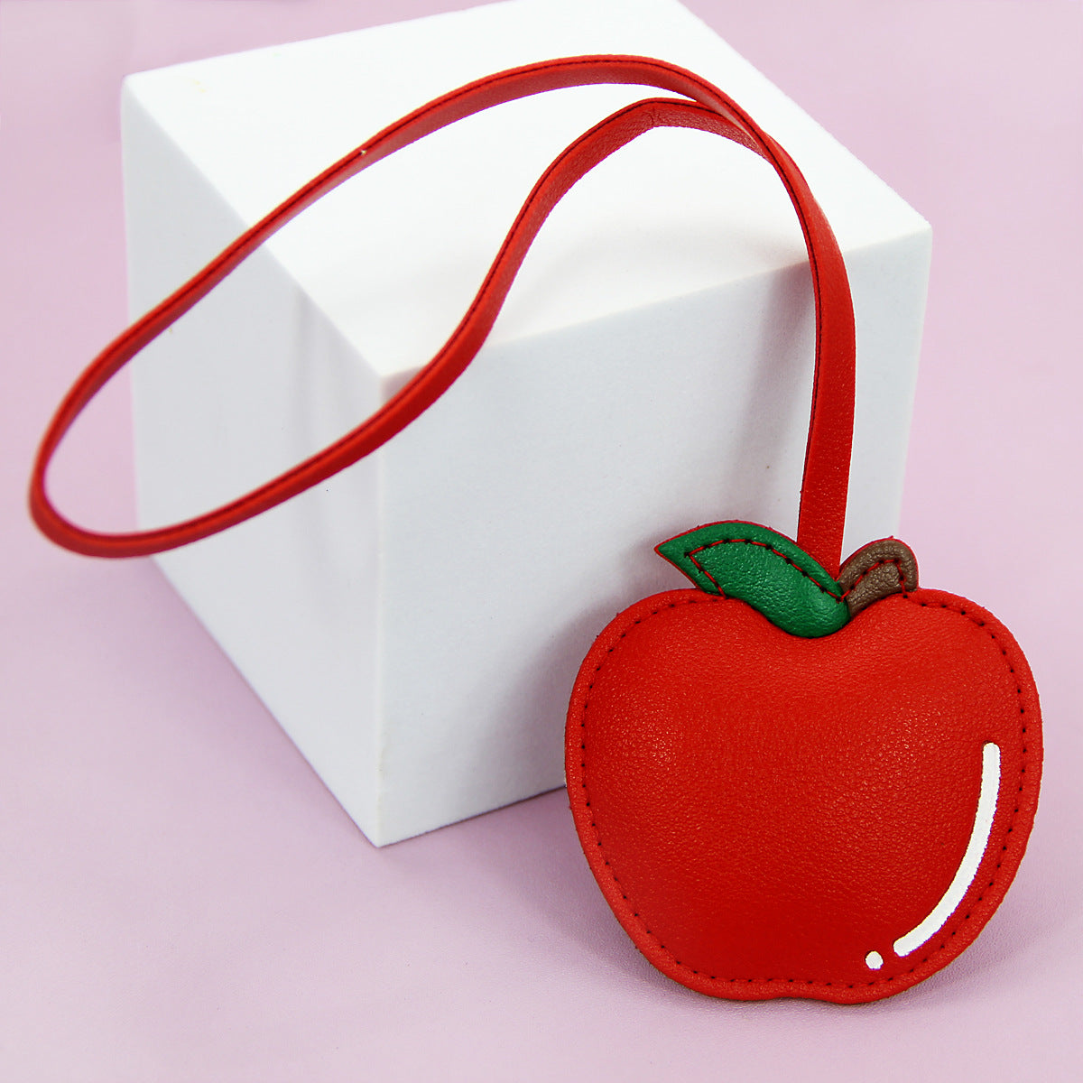 A red apple-shaped PU leather keychain with a green leaf, perfect as a bag charm.