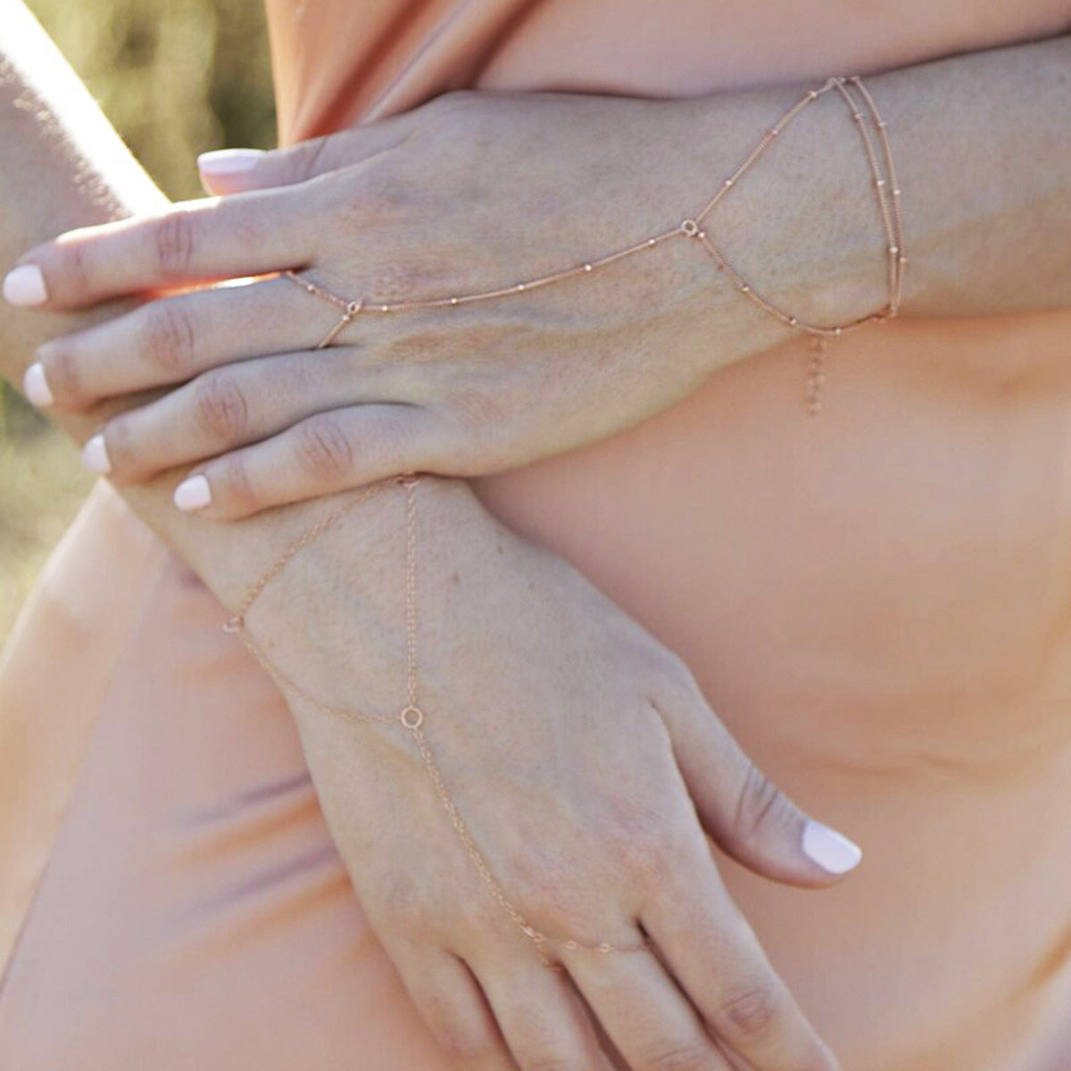 A model's hands adorned with multiple gold-plated bead chain bracelets