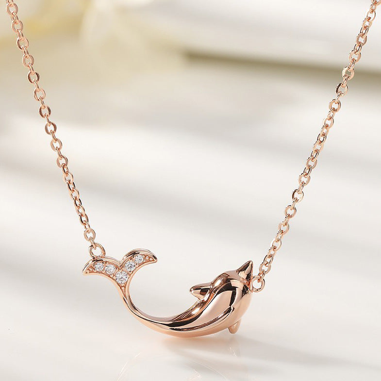 Close-up of the rose gold dolphin pendant on a matching chain