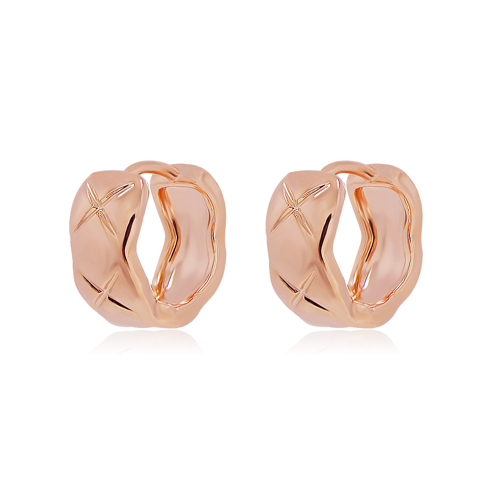 Detailed view of the Rose Gold Huggie Hoop Earrings on a neutral background
