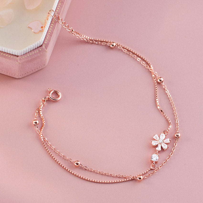 A detailed studio shot of the rose gold double-layer bracelet with a flower charm.