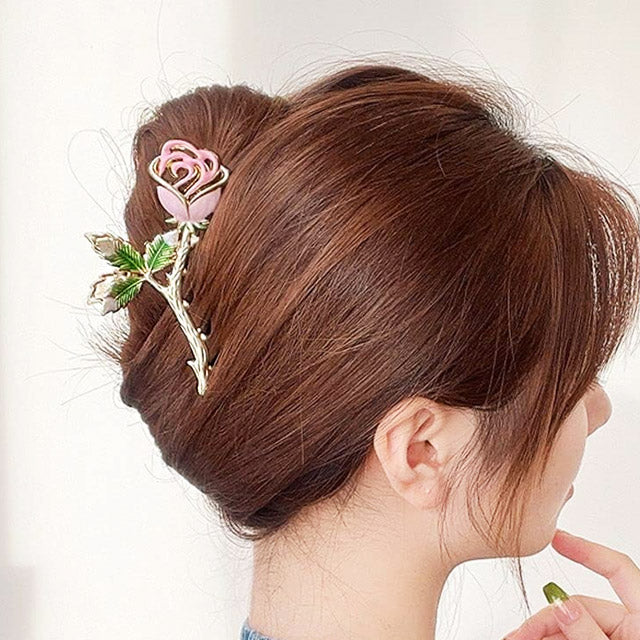 A woman with an elegant updo secured by a rose-shaped hair clip.