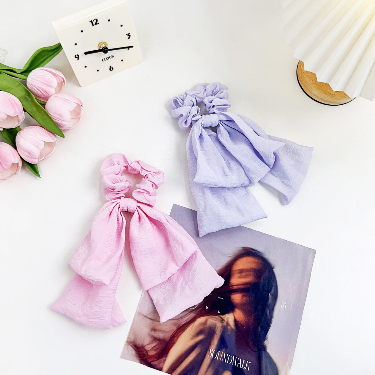 Stylish pink and purple scrunchies displayed next to a magazine