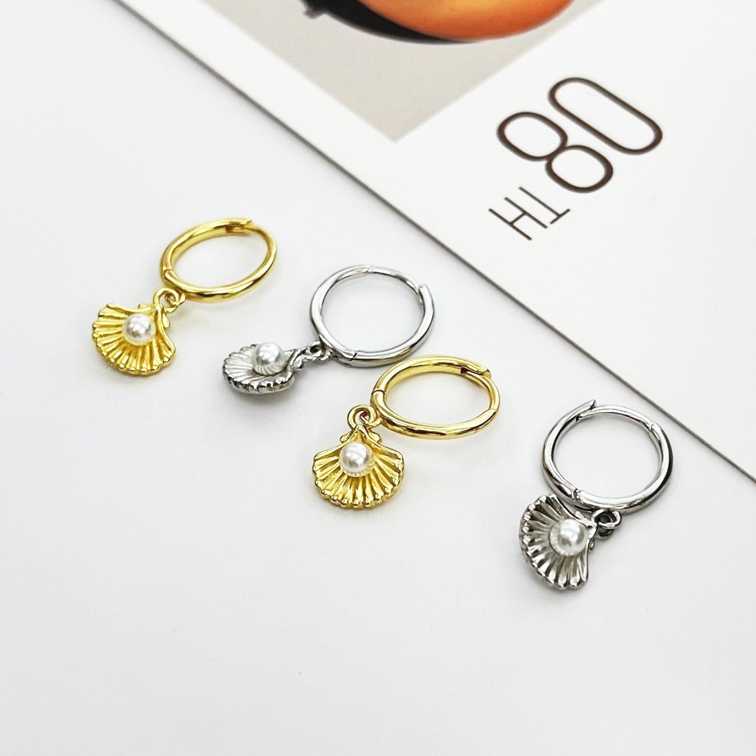 A display of 925 sterling silver ocean pearl shell earrings in both gold and silver finishes