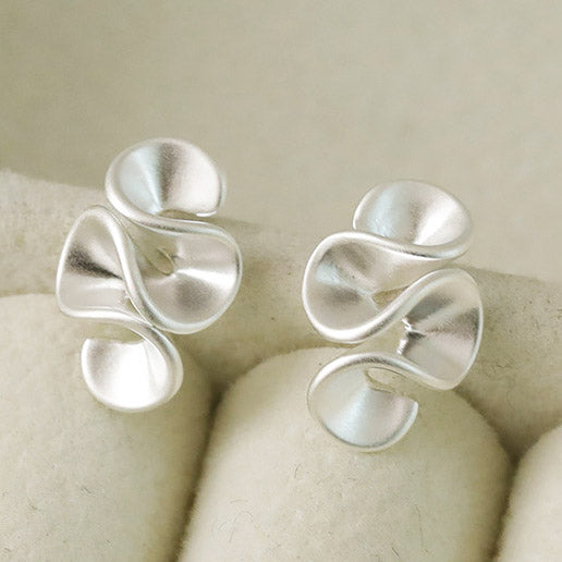 Detailed top-down view of the matte silver geometric earrings.