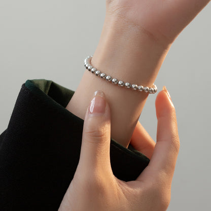 A model's wrist adorned with the stackable 925 sterling silver pearl bracelets.