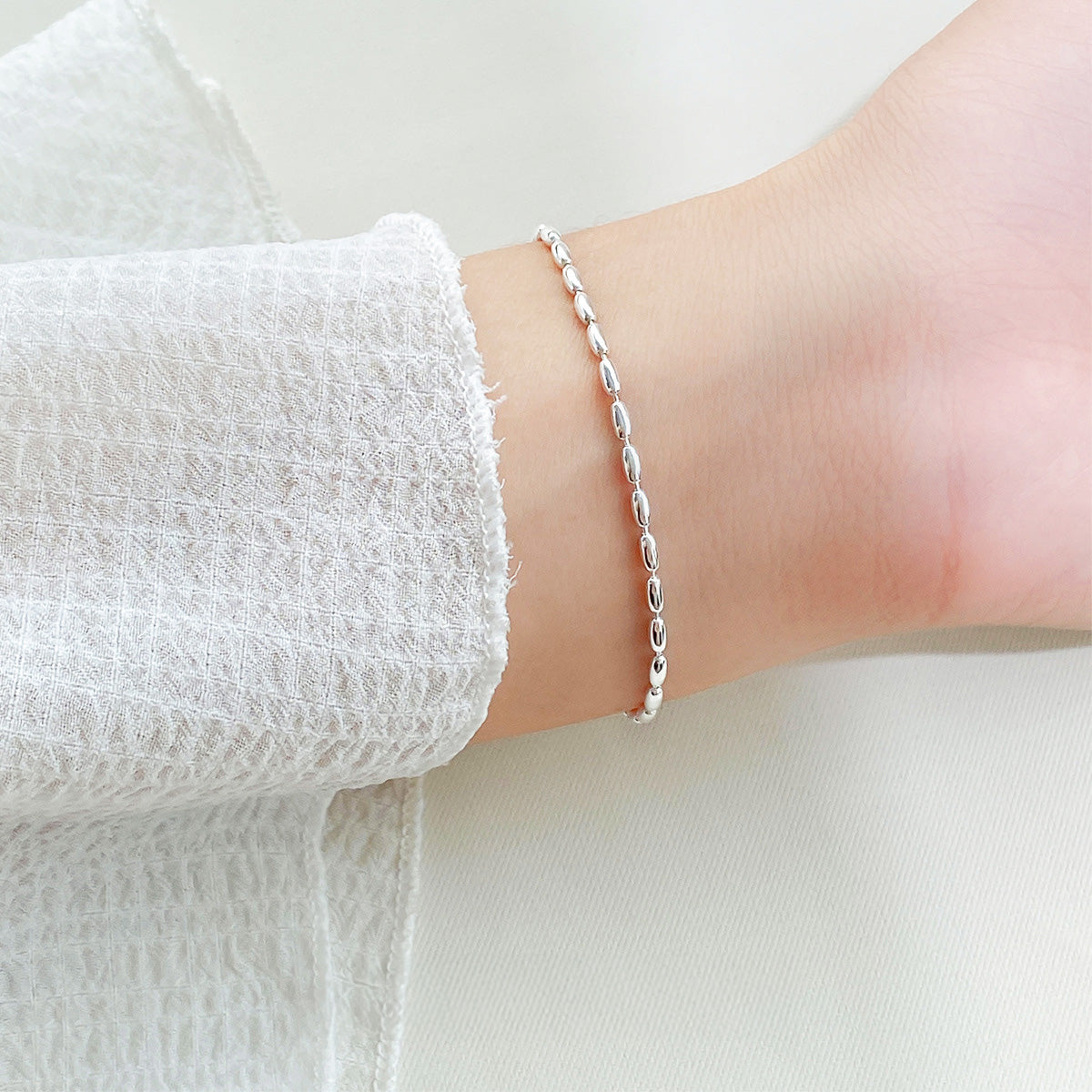 A woman wearing the Simple Beauty 925 sterling silver rice beaded bracelet, showcasing its elegant fit.