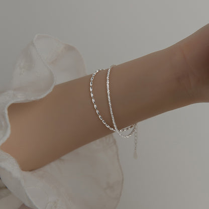 Model showcasing the layered look of the 925 sterling silver bracelet set on her arm.