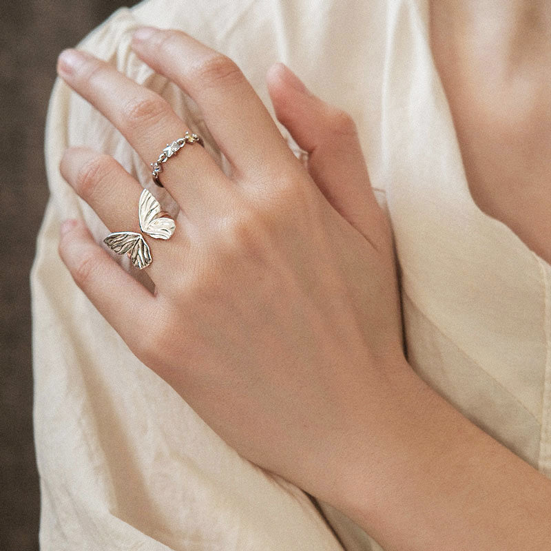 A detailed look at the silver butterfly ring and a complementary stone band from the collection.