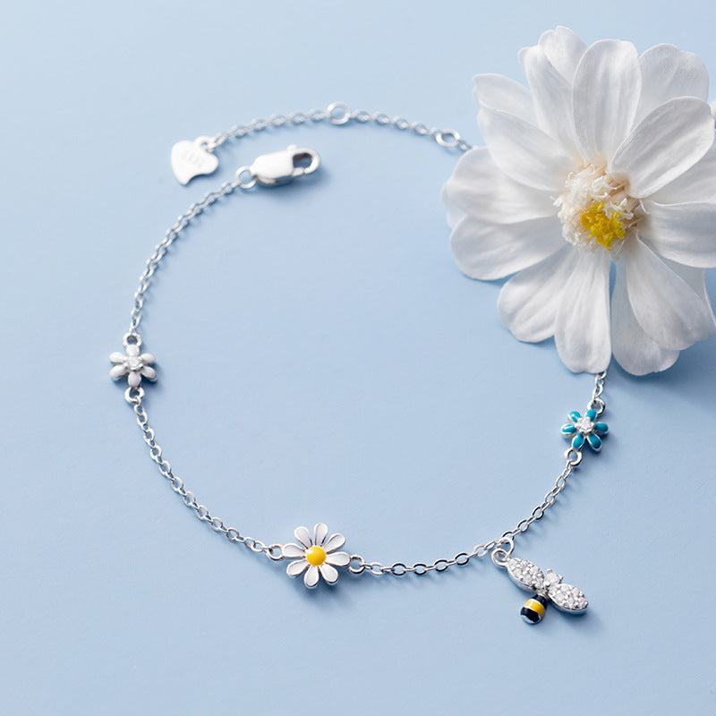 A detailed view of the 925 sterling silver charm bracelet featuring daisy and bee charms with zircon accents.