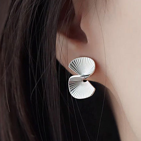 A close-up of the intricate double fan-shaped design of the silver earring.