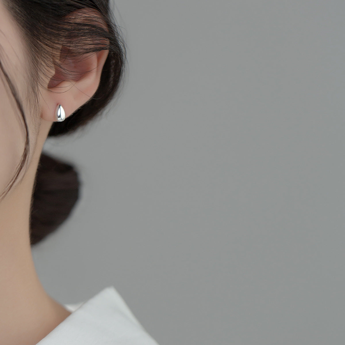 Close-up of the silver water-drop stud earrings on ear