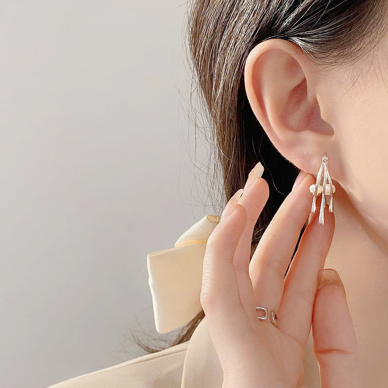 Close-up of the sterling silver pearl drop earring on a model's ear.