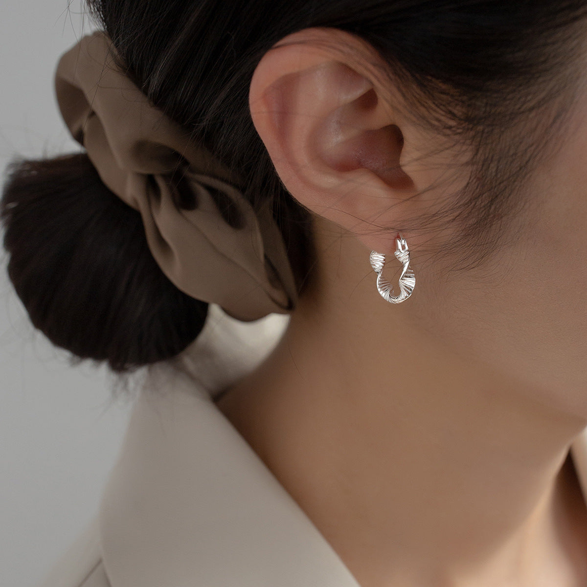 A model wearing the 925 sterling silver twisted hoop earring to showcase its elegant look.
