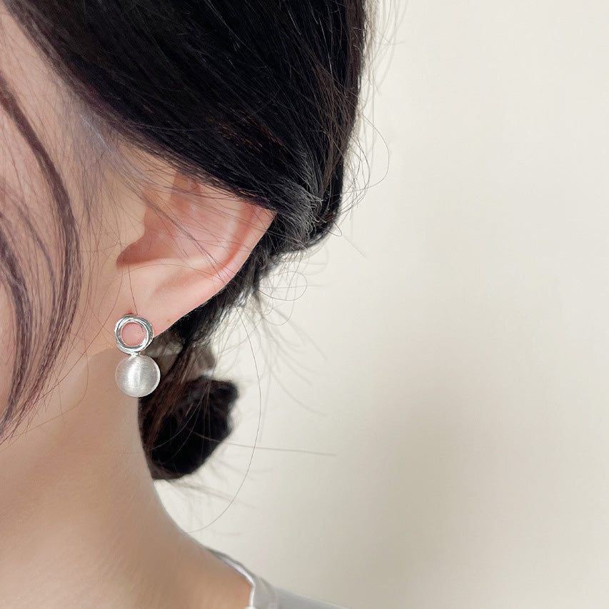 A model wearing the matte silver 3D ball stud earring.