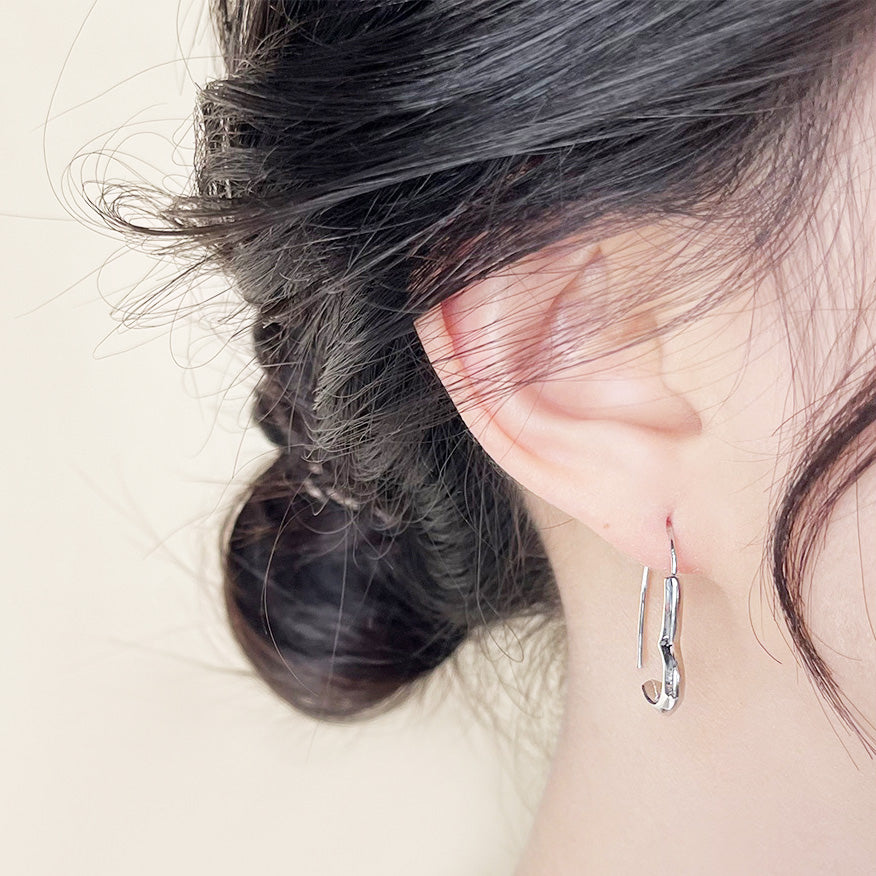 A model showcasing the elegant fit of the silver heart line hoop earring.