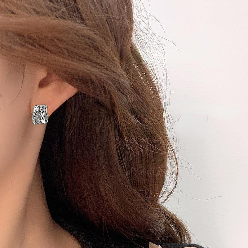 Model wearing an irregular shaped silver stud earring