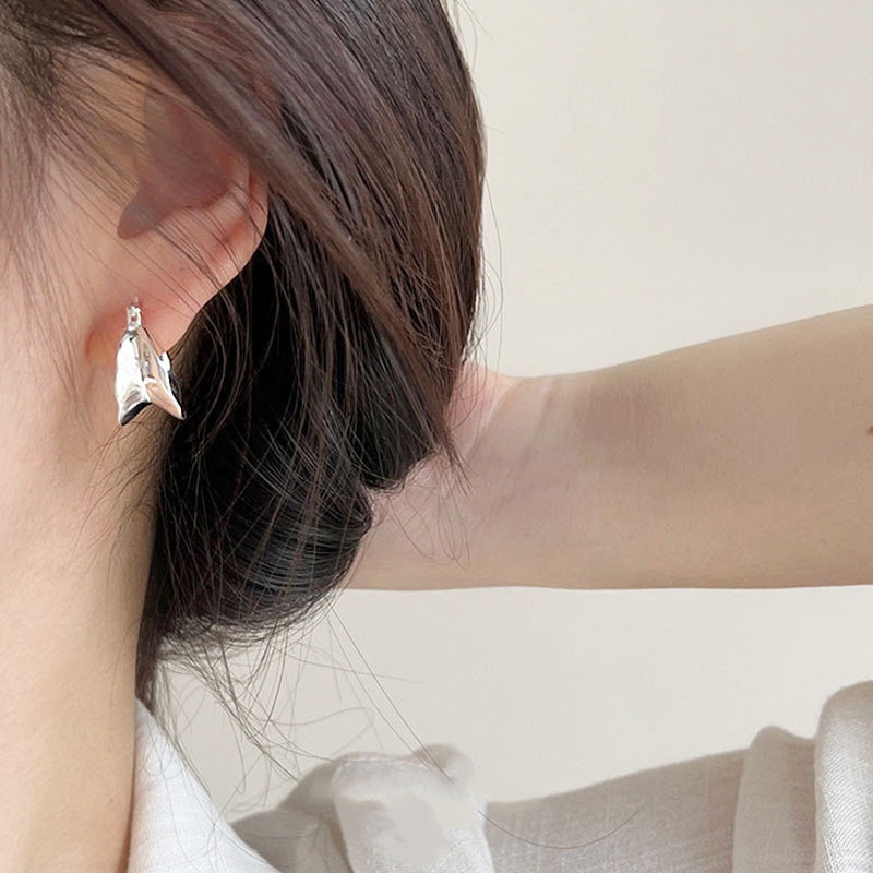 A model showcasing the elegant fit of the 925 sterling silver wide wave hoop earrings.