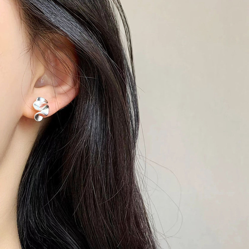 A woman models the stylish brass wave geometric matte silver earrings.