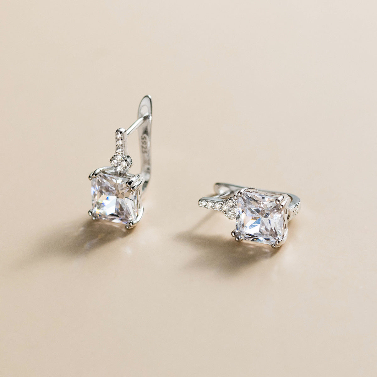 A pair of elegant silver earrings with large, clear gemstones in a minimalist design.