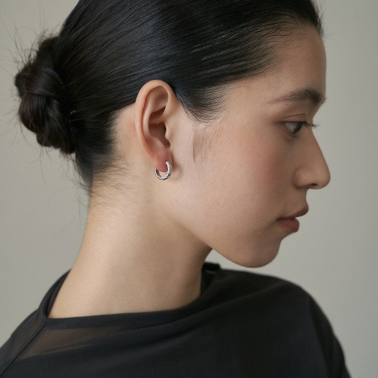 A model's profile view showcasing the sterling silver quilted hoop earrings.