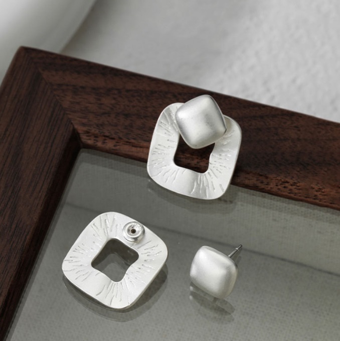 A collection of sterling silver earrings displayed on a wooden frame