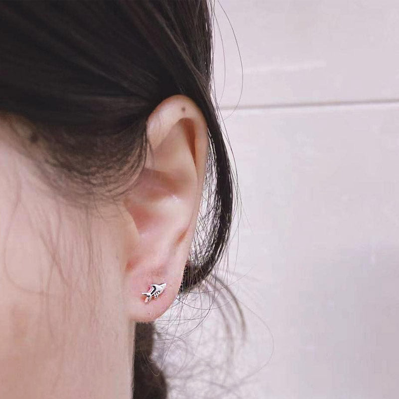 A model wearing a tiny ocean-themed stud earring.