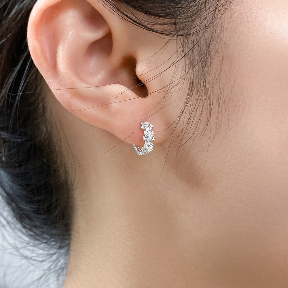 A model showcasing the elegant fit of the sterling silver camellia hoop earrings.