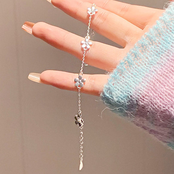A sterling silver flower charm bracelet worn on a hand, showcasing its delicate design.