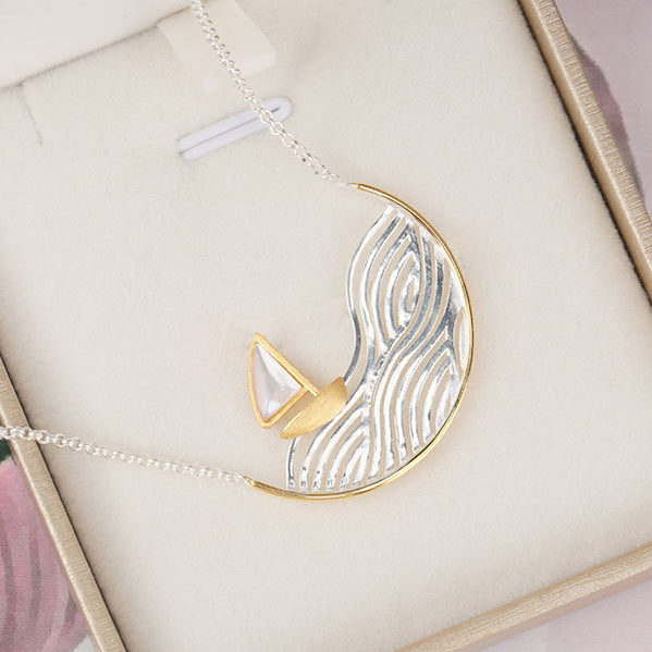 Sailboat pendant necklace displayed in its packaging