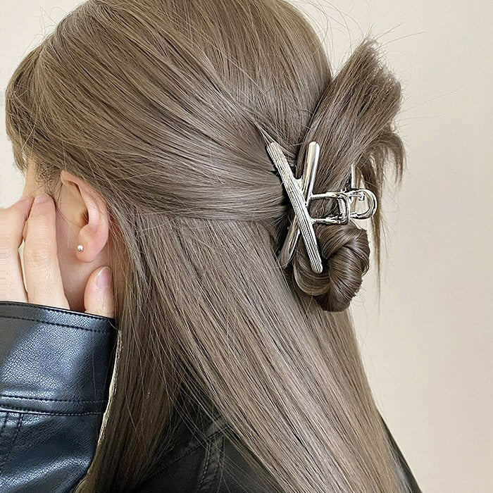 A woman with long brown hair styled in a half-up bun using the silver cross-hair clip.