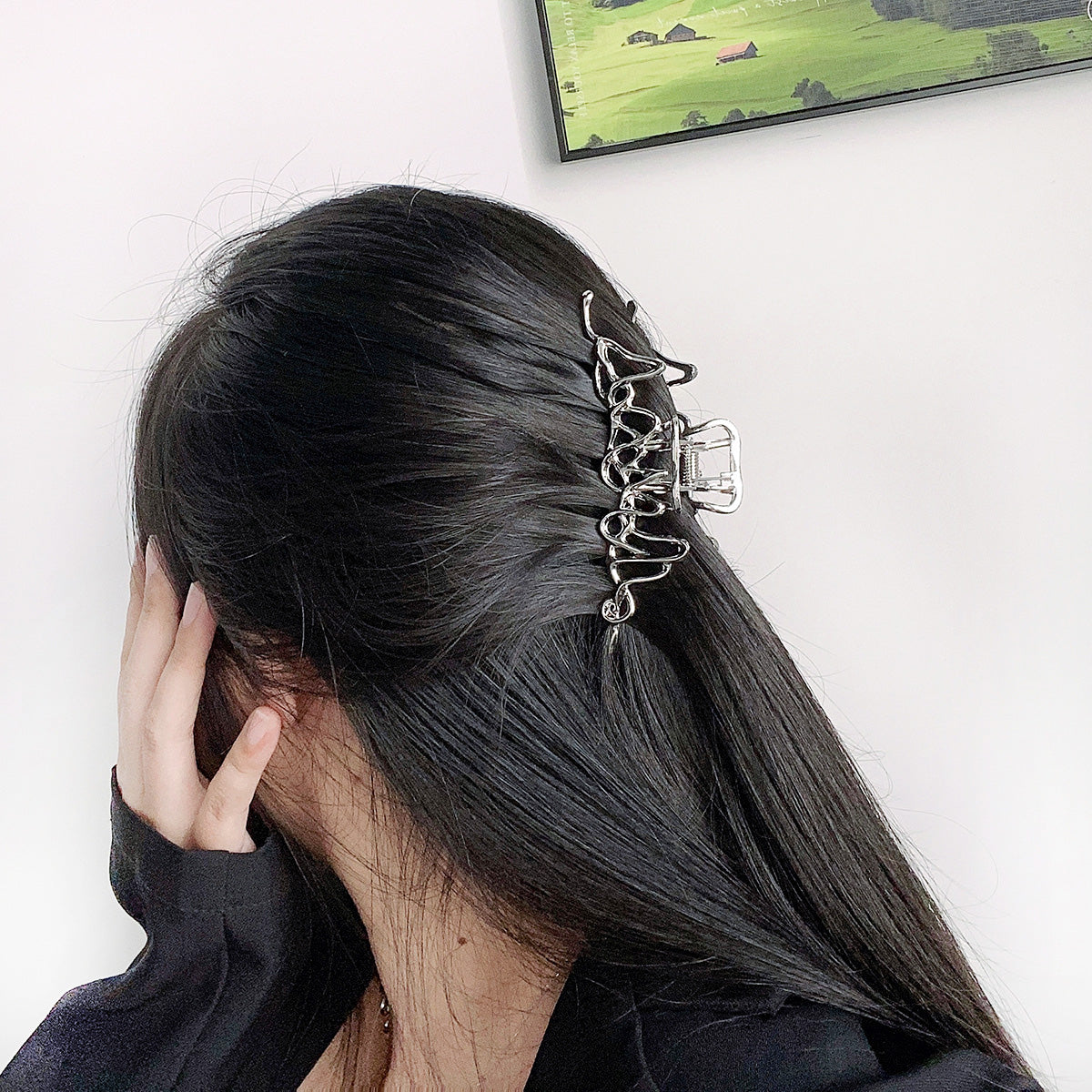 A woman with long black hair wearing a large silver geometric hair clip.