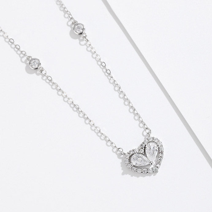 A sterling silver heart necklace with sparkling gemstones on a white background.