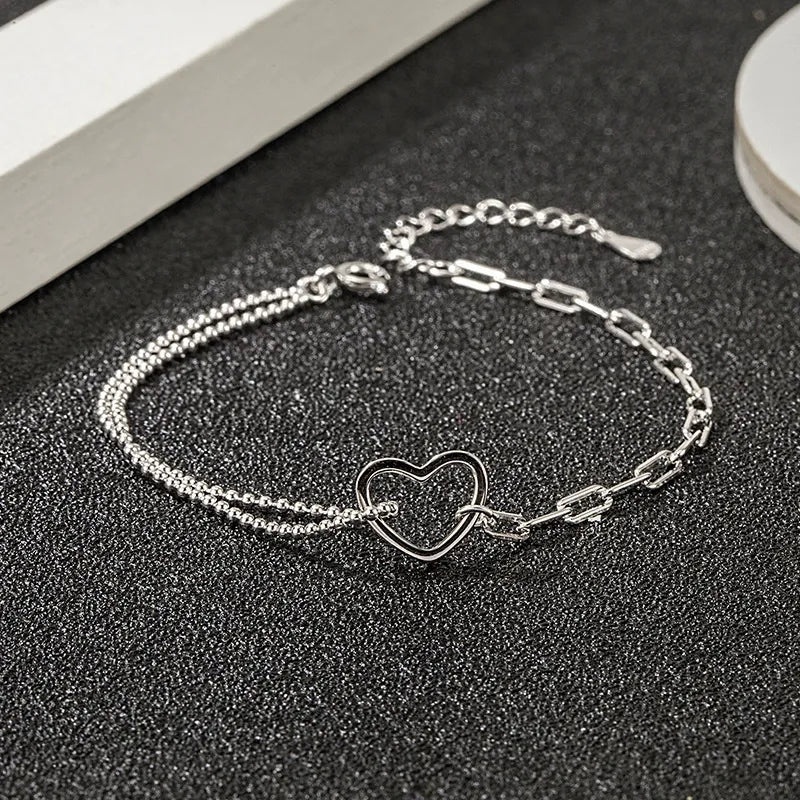 A clear product shot of the 925 sterling silver double chain bracelet with an open heart charm.