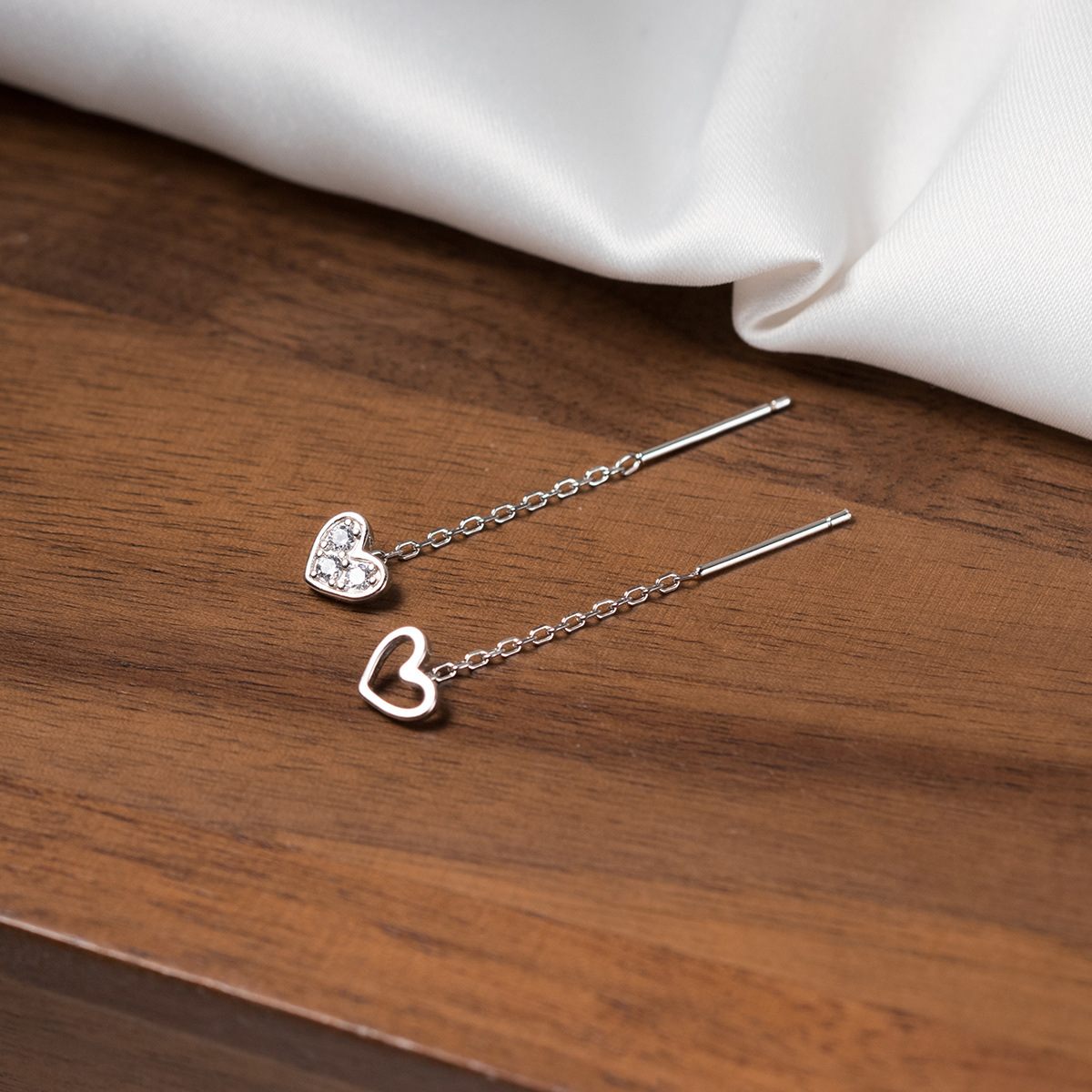 The 5-pack 925 silver heart earring set displayed on a wooden background, ideal for wholesale.