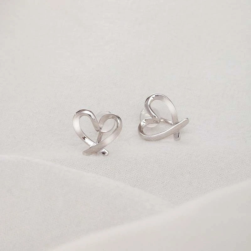 Detailed view of the silver heart-shaped ear clip with an intertwined design