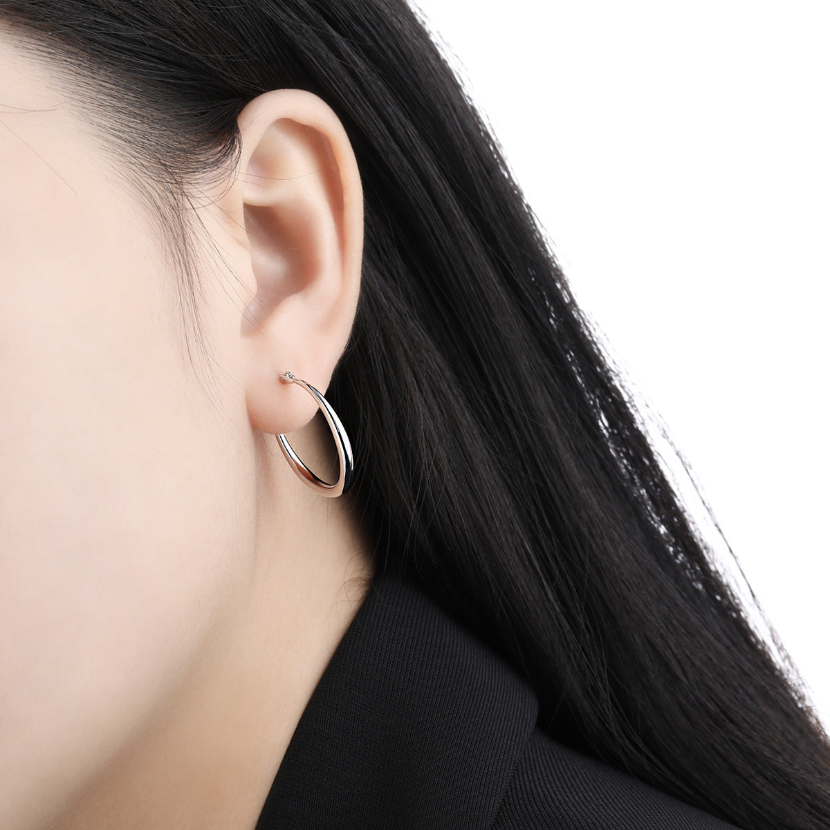 A close-up view of the sleek white gold plated hoop earring on a model.