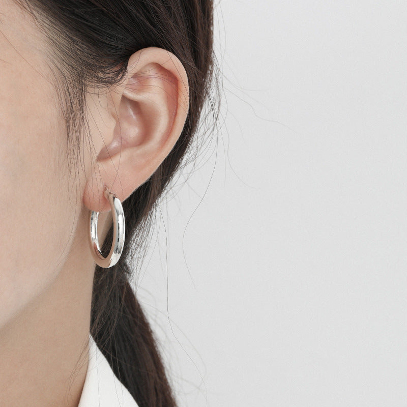 A close-up of the silver thick hoop earring being worn.