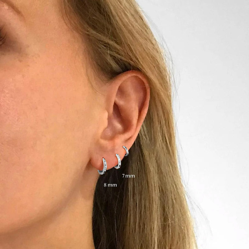 Model wearing different sizes of sterling silver hoop earrings