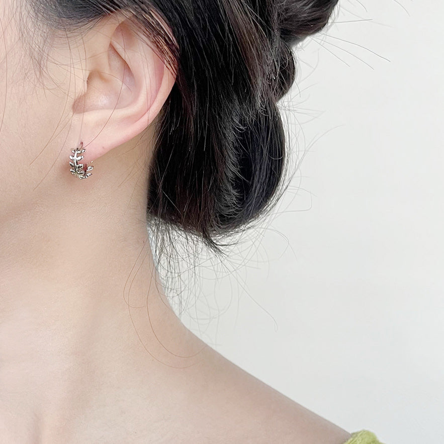 A model wearing the silver plated leaf wreath tiny hoop earring to show its scale and style.