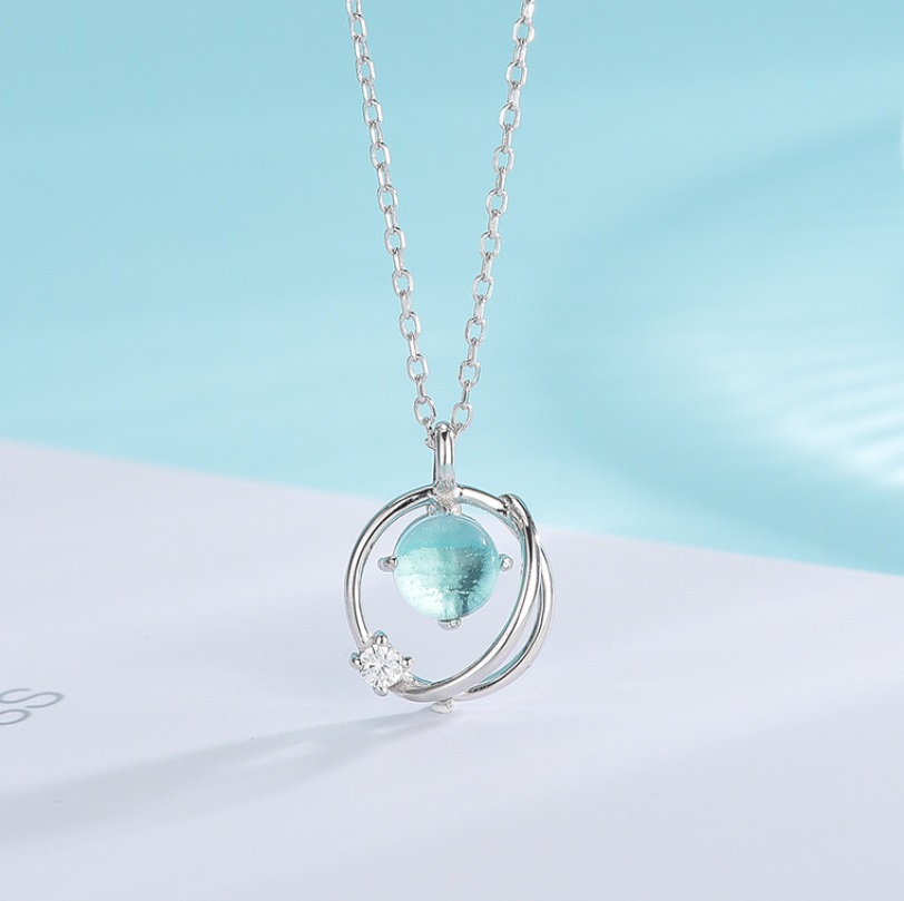 Detailed view of the blue-green gemstone pendant on the silver necklace