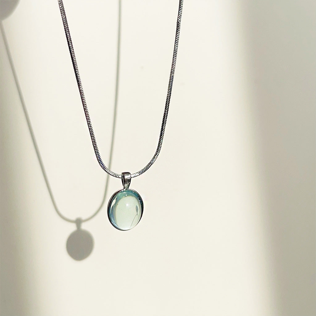 Detailed view of the silver snake chain and oval glass pendant
