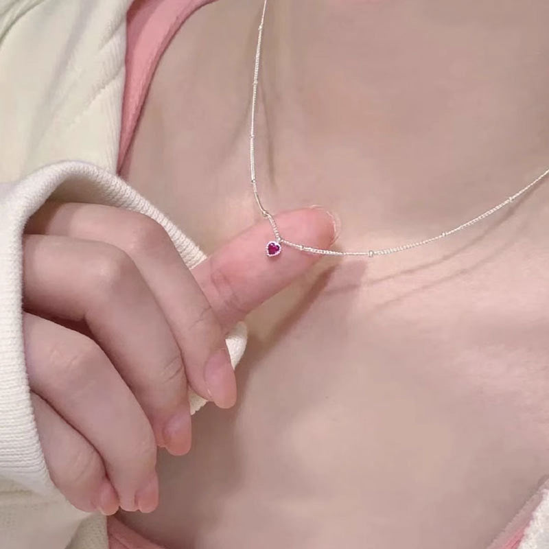 A model showcasing the delicate 925 sterling silver necklace with a purple zircon heart pendant.