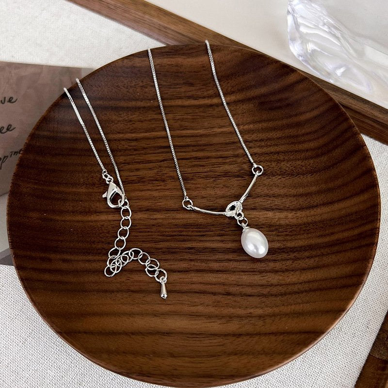 A pair of silver-plated pearl necklaces displayed to showcase the design