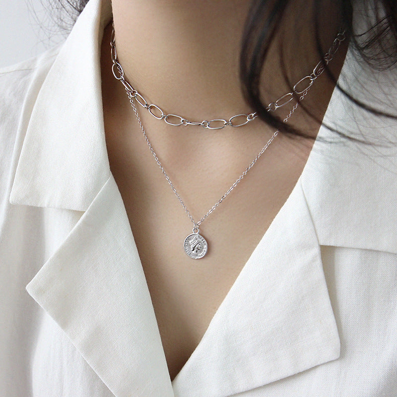 A model showcasing the layered style of the silver vintage coin portrait pendant necklace.