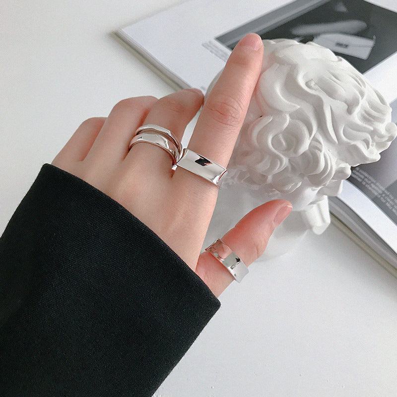 A model's hand showcasing multiple stacked geometric silver rings from the collection.