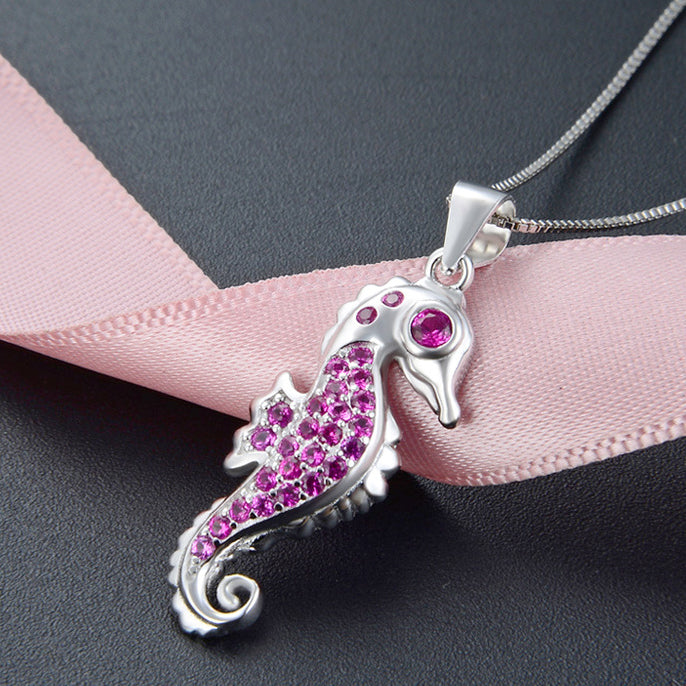 Side view of the sterling silver seahorse necklace showcasing the pink gemstones.