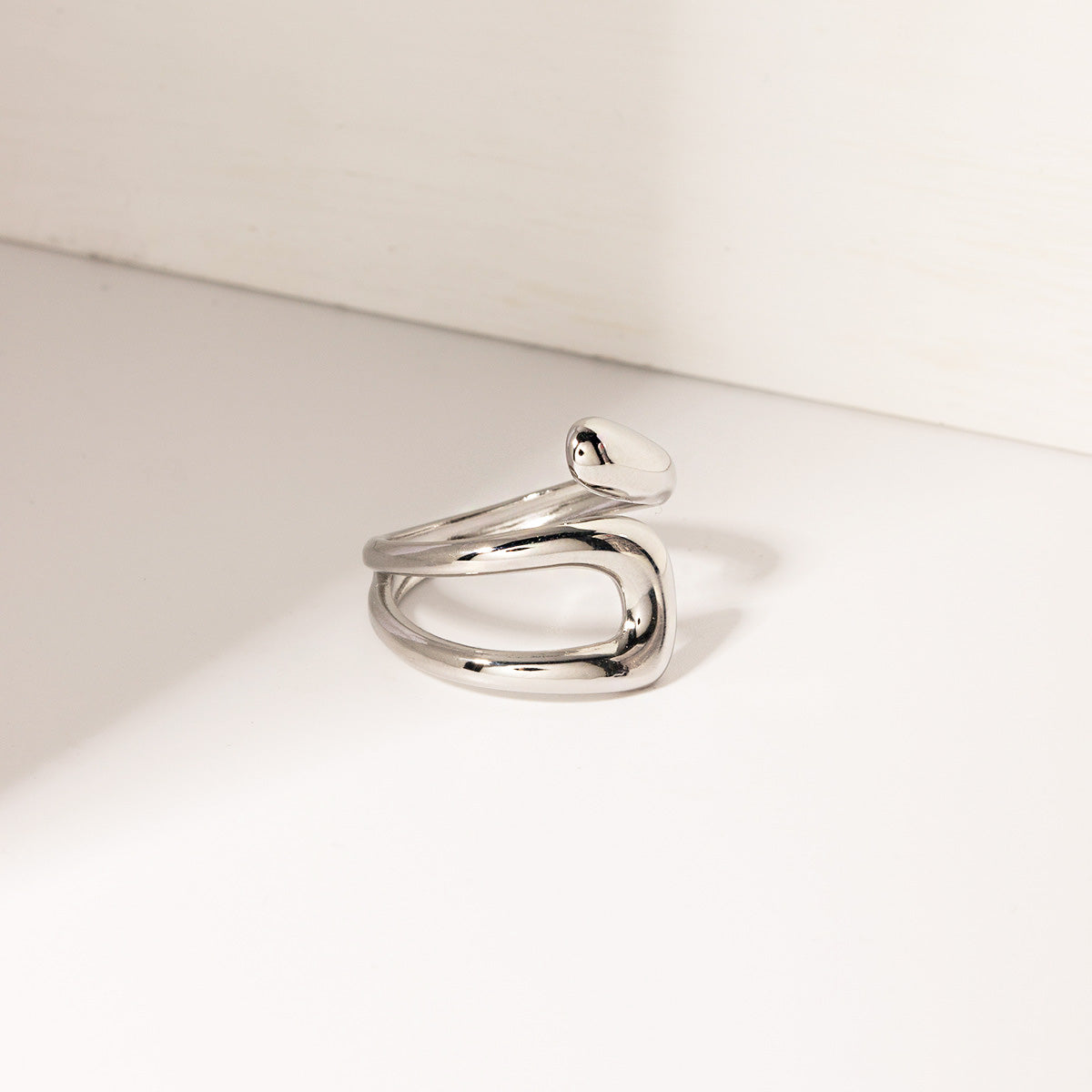 A collection of five stainless steel geometric rings displayed together.