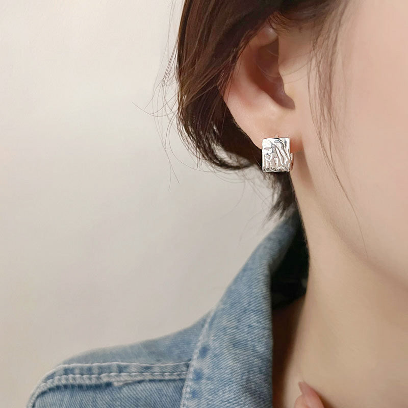 A woman showcasing the elegant fit of the sterling silver geometric square huggie earring.