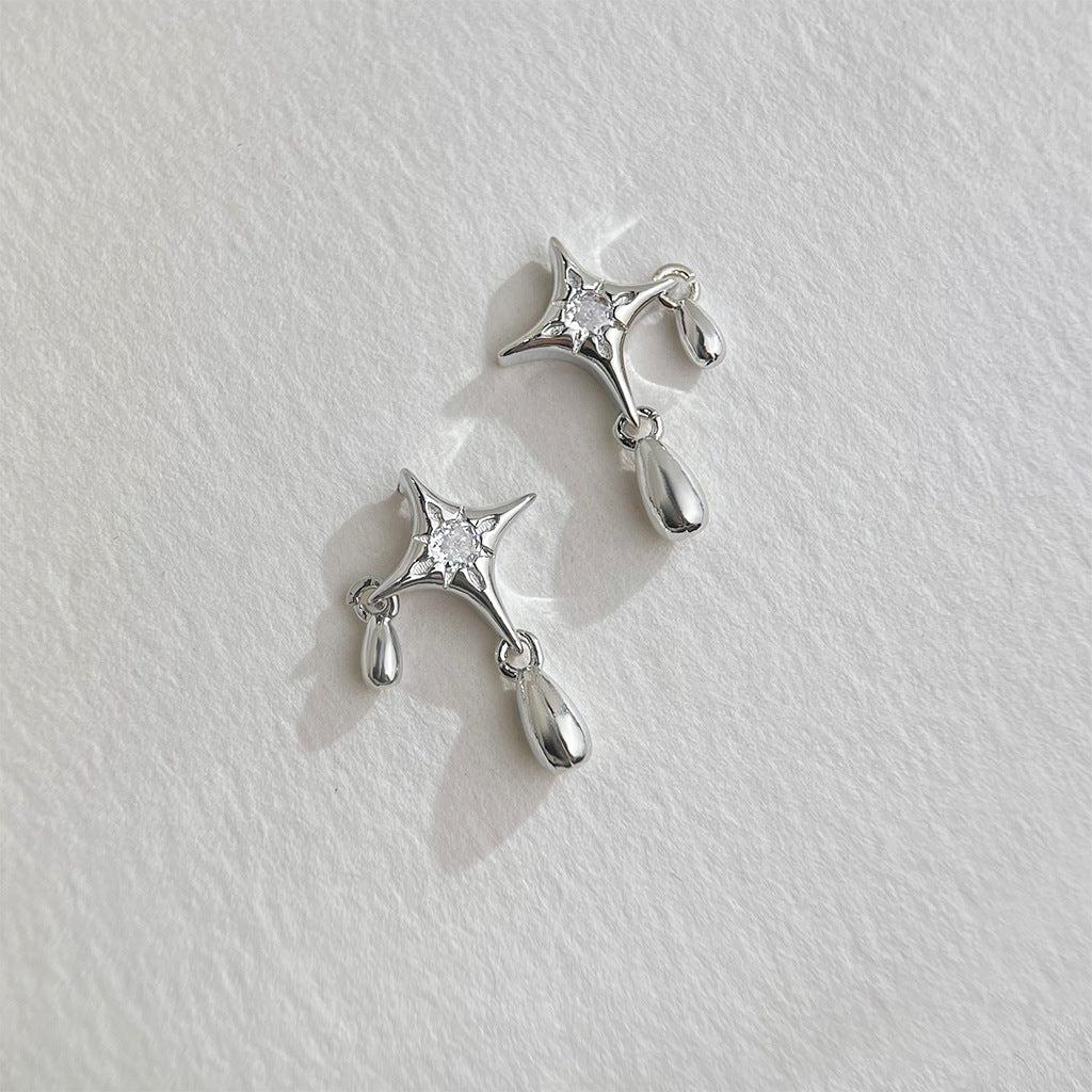 Detailed close-up of the silver star drop earring with a teardrop charm